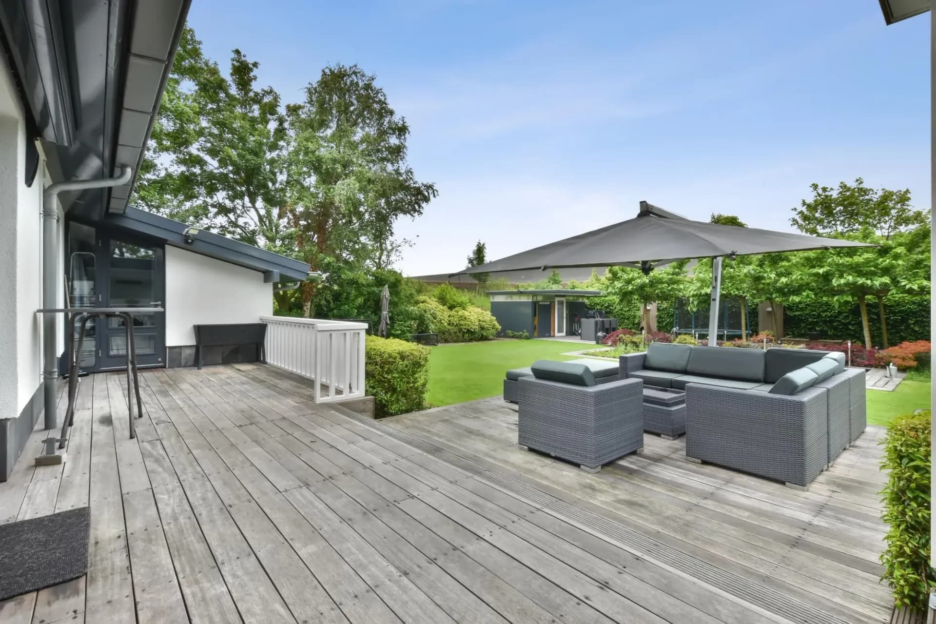 A wide shot of a wood deck with patio furniture overlooking a yard.