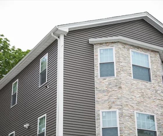 A house with gray siding and white trim with a light-colored stone section on the right side.