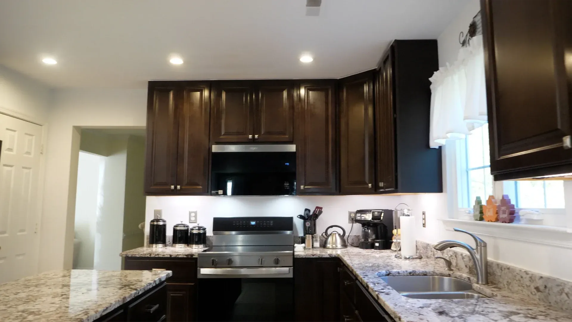 A photo of a stove in a kitchen with dark brown cabinets.